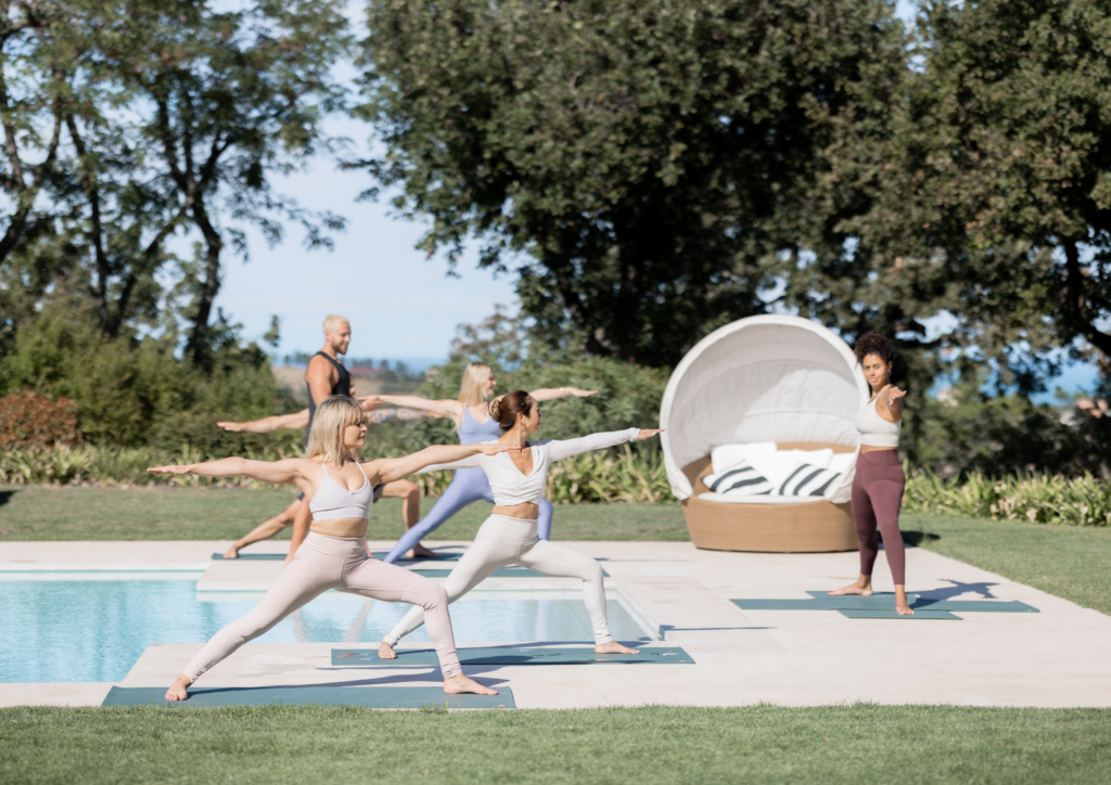 Retreat guests doing yoga by the pool